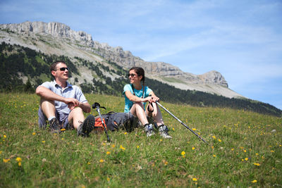 Friends sitting on grass against mountains