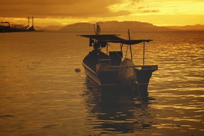 Boat moored in sea against sky during sunset