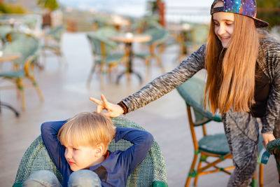 Teenage girl doing rabbit ears gesture on brother head