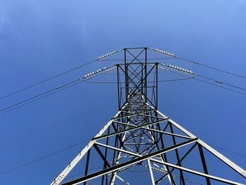 Low angle view of electricity pylon against clear blue sky