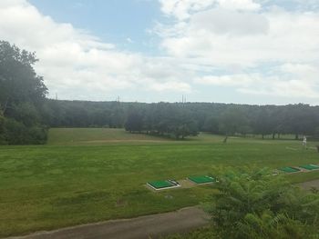 Scenic view of grassy field against cloudy sky