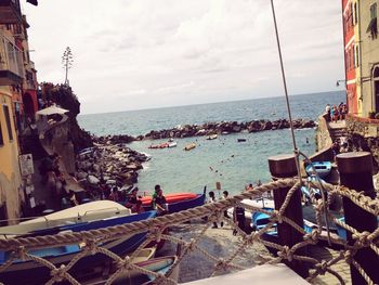 Boats in sea against cloudy sky