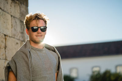 Young man wearing sunglasses standing against clear sky