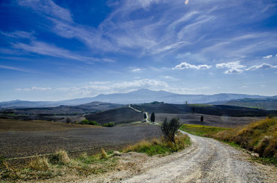 Road by landscape against blue sky