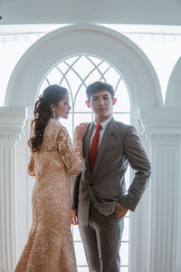 Portrait of bride and bridegroom standing against building