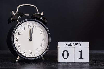 Close-up of alarm clock with calendar on table