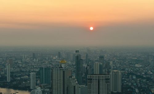 Aerial view of city buildings against sky during sunset