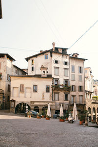 Houses by buildings in city against clear sky