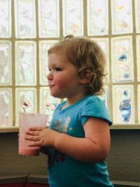 Side view of girl with drink standing at home