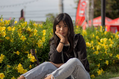 Portrait of young woman against flowering plants