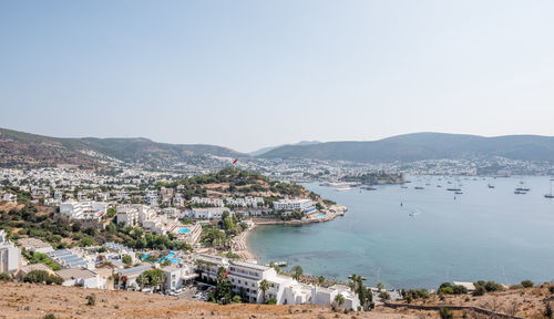 Aerial view of townscape by sea against clear sky