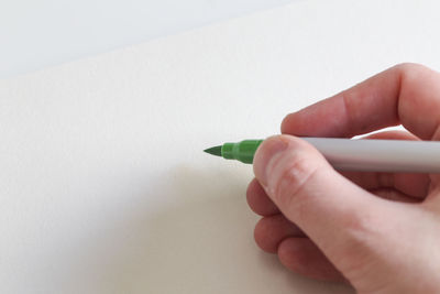 Close-up of hand holding pencils against white background