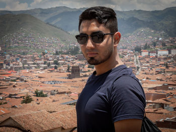 Portrait of young man standing by cityscape in city