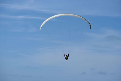 Low angle view of person paragliding against sky