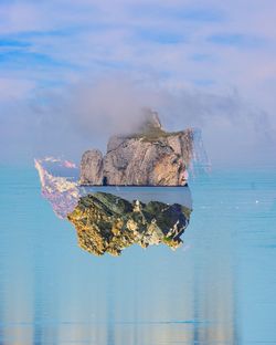 Digital composite image of rocks and sea against sky