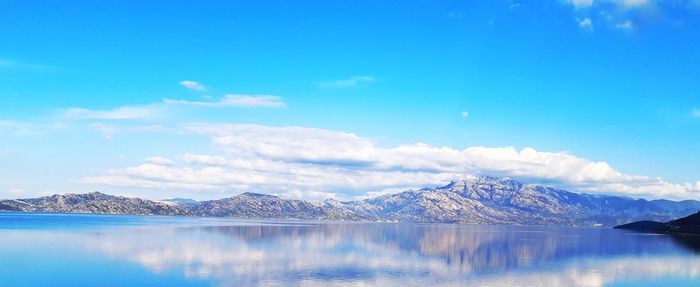 Scenic view of lake and mountains against blue sky