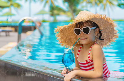 Girl with sunglasses having drink in swimming pool