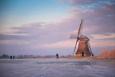 Man standing on snow covered land against sky during sunset