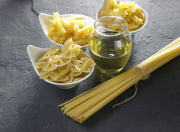 Various pasta with oil in jar on slate