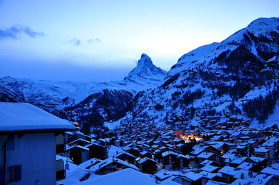 Houses on snowcapped mountain against sky