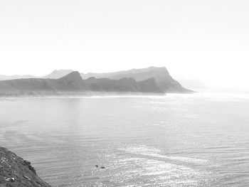 Scenic view of sea and mountains against clear sky