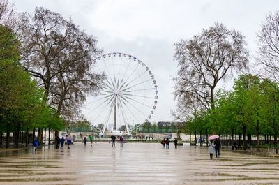Tourists on the tuileries garden on a rainy day against the paris wheel in springtime 