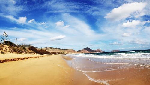 Scenic view of beach against cloudy sky