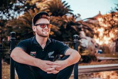 Portrait of young man wearing sunglasses standing against sky