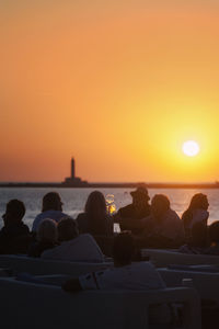 People sitting on beach during sunset
