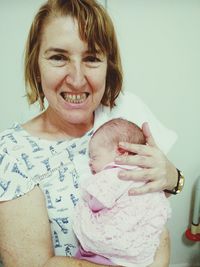 Portrait of happy mother holding baby at home