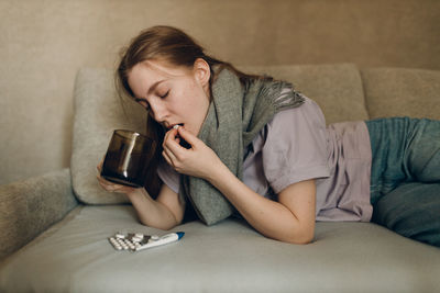 Young woman using mobile phone while sitting on sofa at home