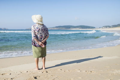 Back view of senior woman standing on the beach