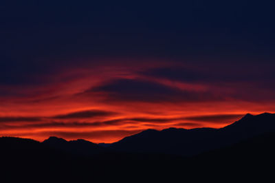 Scenic view of silhouette mountains against orange sky