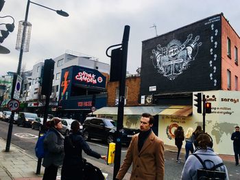 People walking on street in city against sky