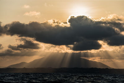 Sunlight streaming through clouds over sea