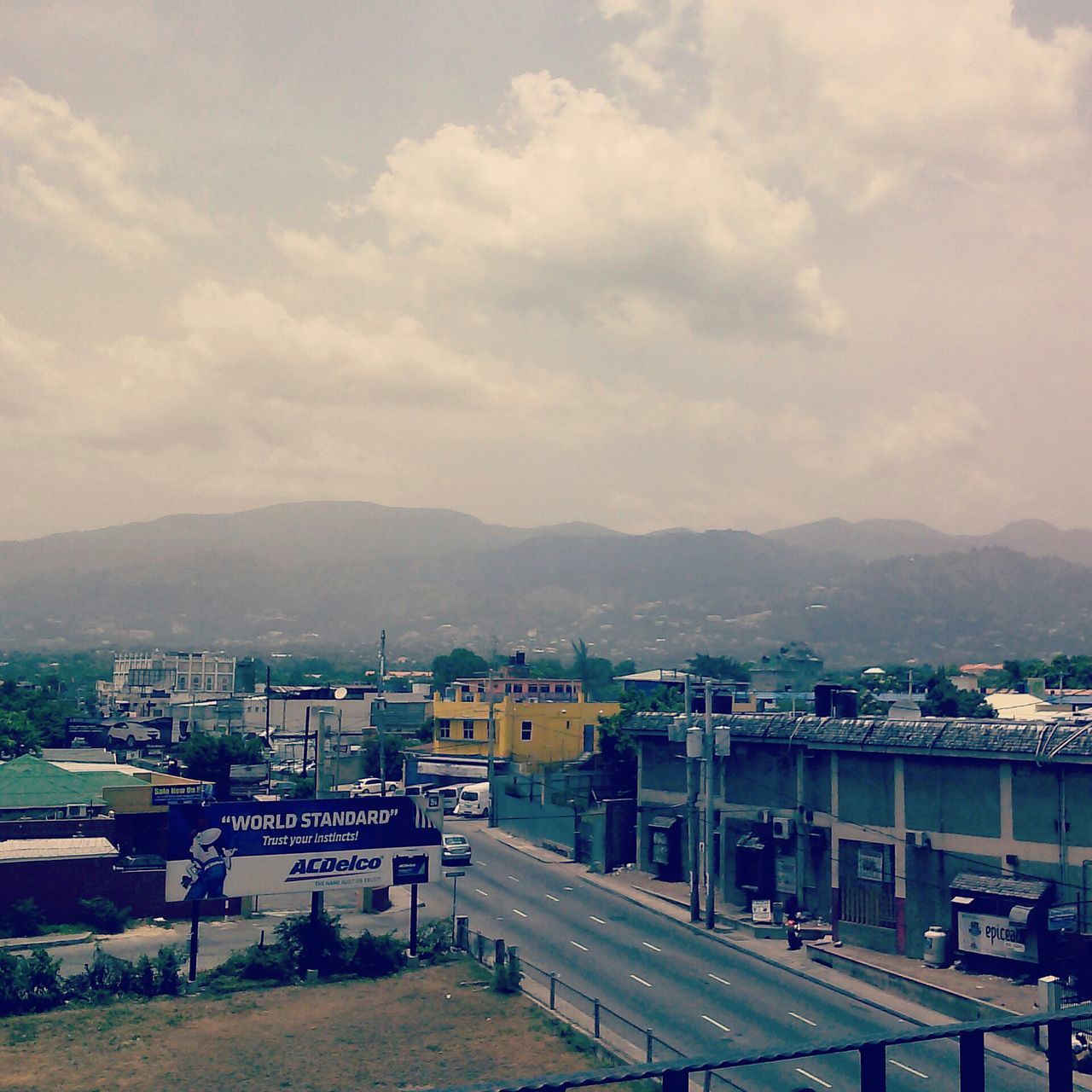 mountain, sky, building exterior, architecture, built structure, mountain range, transportation, cloud - sky, road, car, city, cloudy, cloud, street, landscape, high angle view, residential structure, house, town, land vehicle