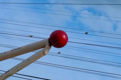 Low angle view of red and cables against blue sky