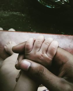 Close-up of father holding baby hand