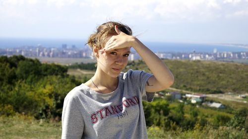 Portrait of young woman standing against sky