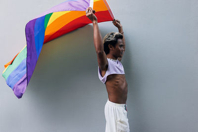 Rear view of woman holding flag against blue background