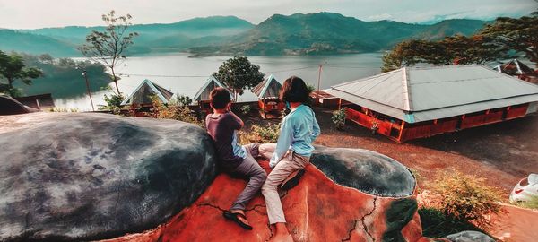 People standing on shore against mountains