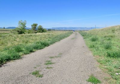 Road amidst field against sky