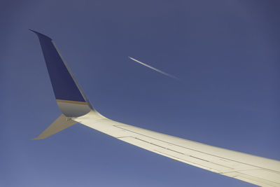 Low angle view of airplane flying against clear blue sky