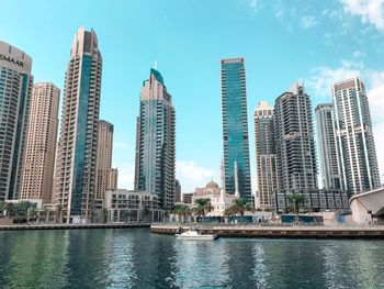 Modern buildings by river against sky in city