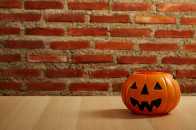 Close-up of pumpkin on table against brick wall