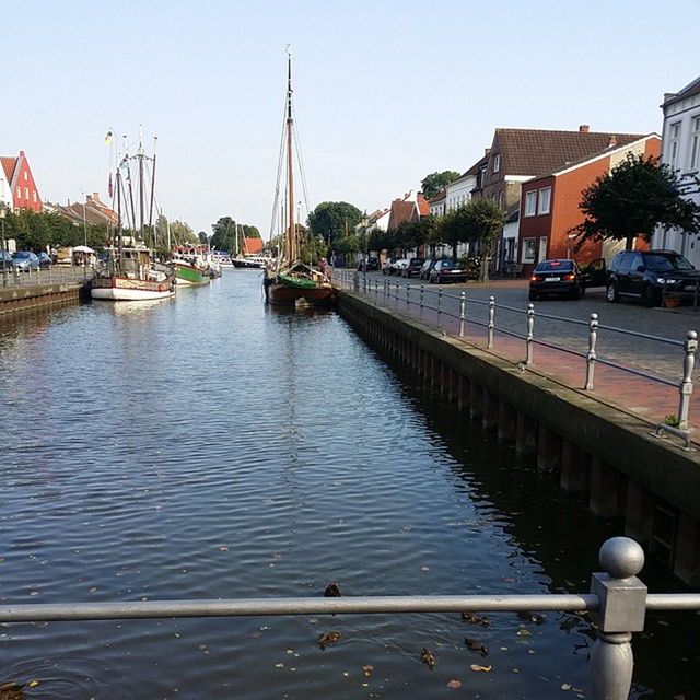 water, transportation, building exterior, nautical vessel, moored, mode of transport, built structure, architecture, boat, harbor, clear sky, city, river, blue, canal, sea, sky, waterfront, tree, incidental people