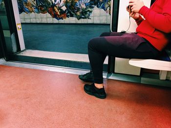 Low section of person sitting on bench by doorway