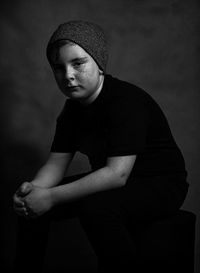 Portrait of teenage boy sitting against sky at dusk