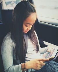 High angle view of teenage girl using digital tablet while sitting in car