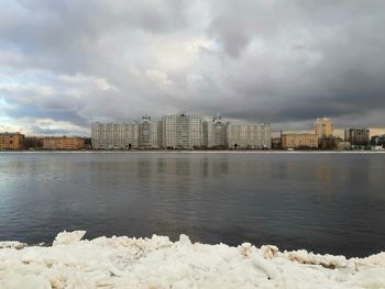 Sea by buildings against sky in city